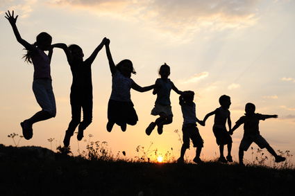 Silhouette, group of happy children playing on meadow,