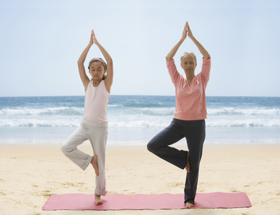 Grandmother and granddaughter practicing yoga on beach