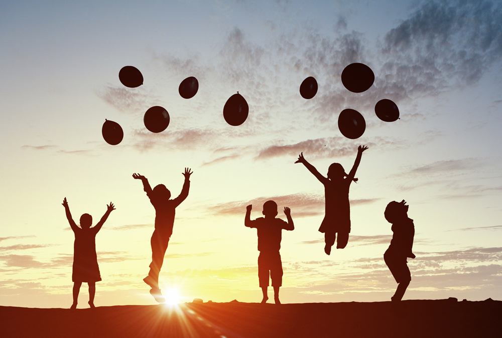 Silhouettes of group of children jumping on sunset background